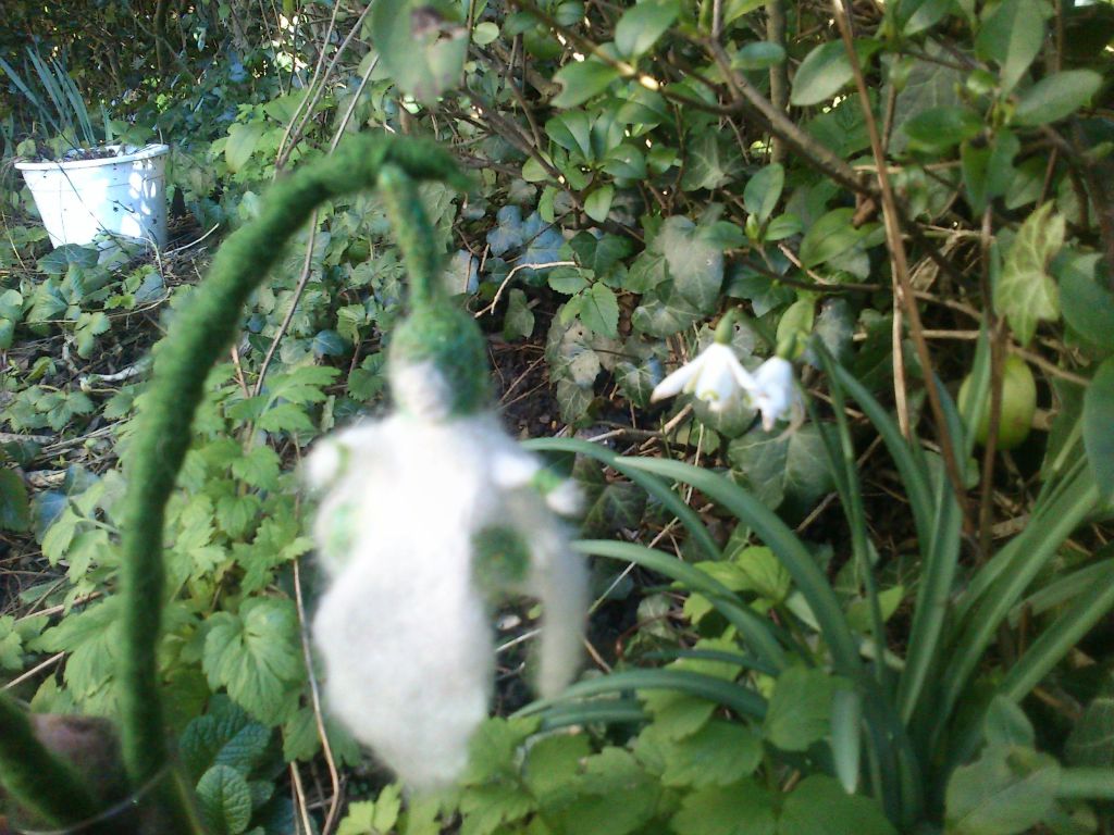 Needle felted snowdrop beside snowdrop flowers